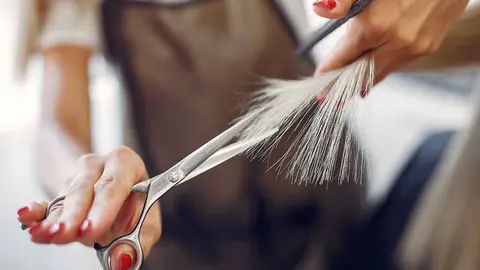 Hairdresser cut hair her client. Woman in a hair salon