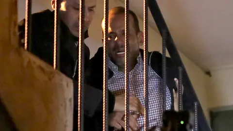 Luis Fernando Camacho (R), a key opposition figure and governor of the economic powerhouse Santa Cruz region, is escorted up a staircase upon arriving at the headquarters of the Special Forces for Fight against Crime (FELCC in Spanish) in La Paz, Bolivia, following his arrest on December 28, 2022. - Bolivian police on Wednesday arrested Luis Fernando Camacho, a key opposition figure and governor of the economic powerhouse Santa Cruz region, the government announced, without specifying the charges. Right-wing civic leader Camacho was under investigation on several charges, including for an alleged role in the resignation of leftist president Evo Morales in 2019, and for allegedly fanning protests in Santa Cruz this year. (Photo by LUIS GANDARILLAS / AFP)